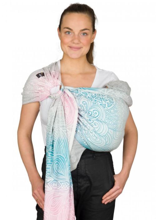 Mãe a utilizar um sling de argolas Hoppediz com padrão colorido e ergonómico.