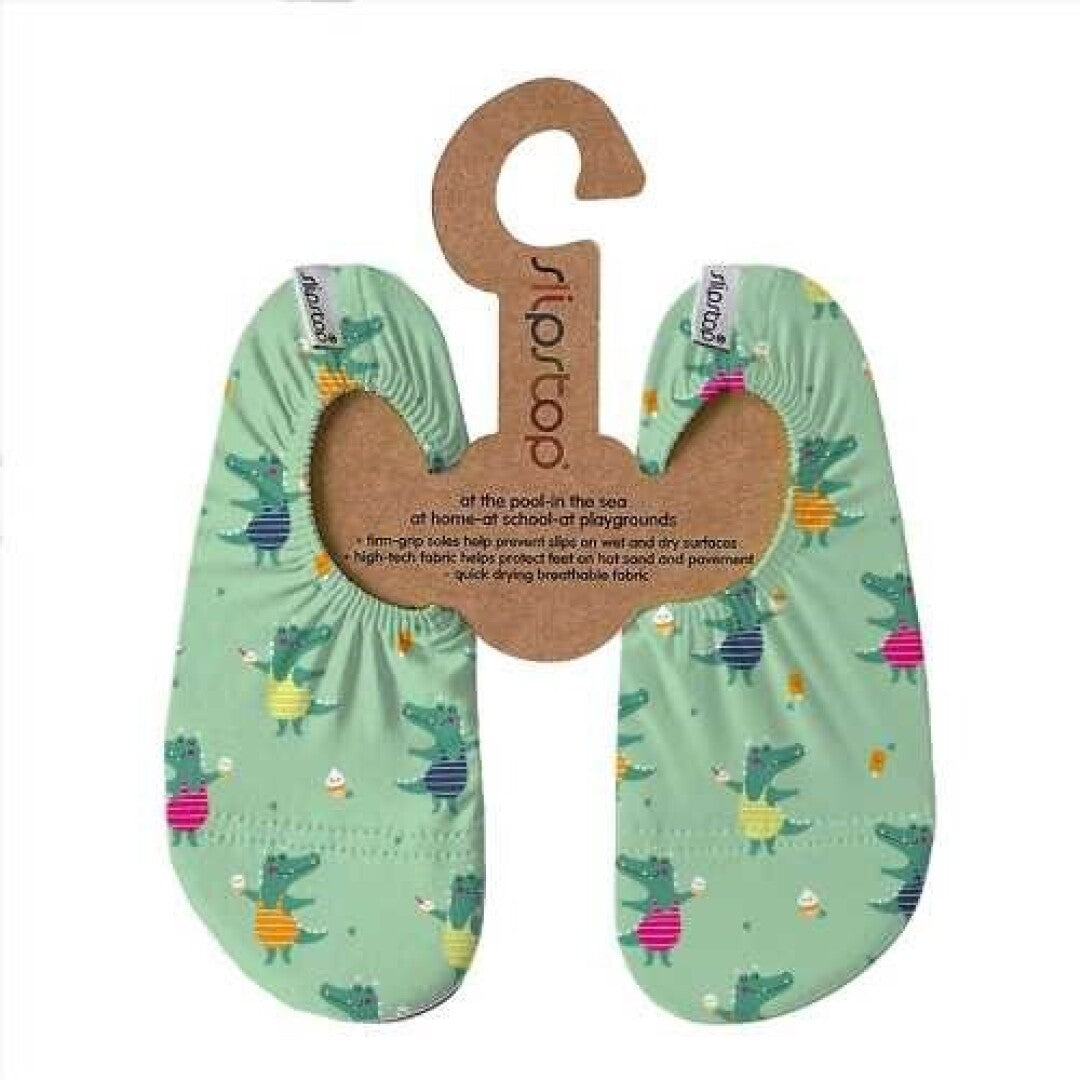 Par de meias Slip Stop antiderrapantes com padrão de crocodilos verdes, apresentadas na embalagem de cartão com o logótipo Slipstop.