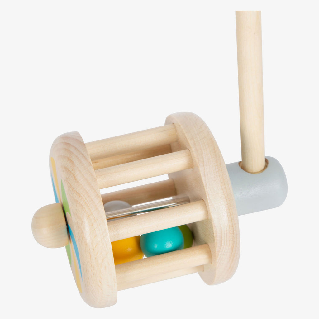 Vista lateral do chocalho de empurrar, destacando a pega ergonómica com pomo redondo e as rodas com efeito visual.