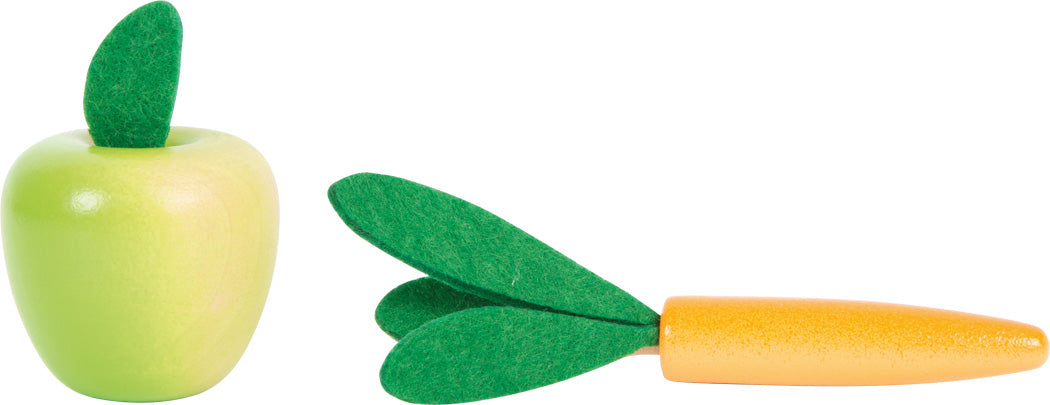 Detalhe dos alimentos de brincar em madeira: maçã verde e cenoura laranja com folhas verdes de feltro, do kit de cuidados de cavalos.