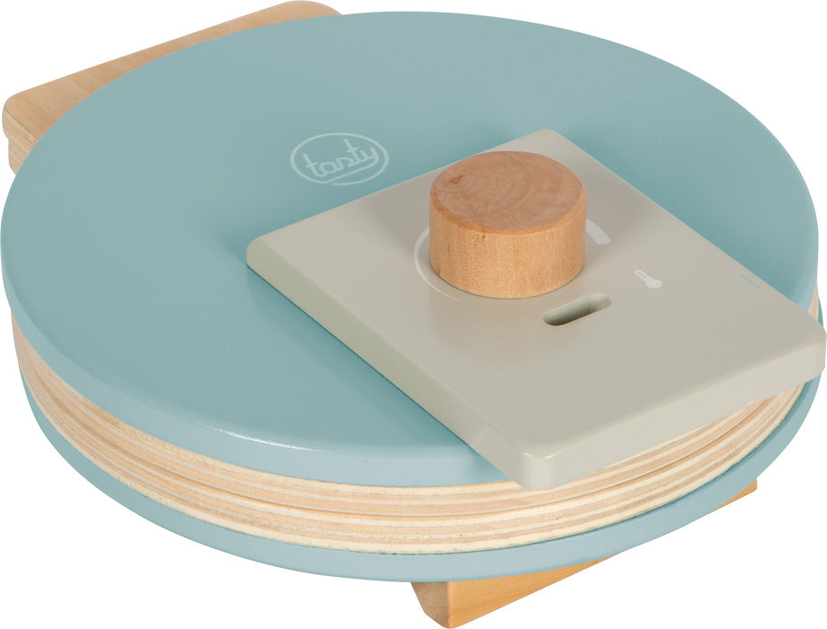 Detalhe da máquina de waffles de brincar fechada, com termostato de madeira ajustável e acabamento em azul-acinzentado estilo escandinavo.