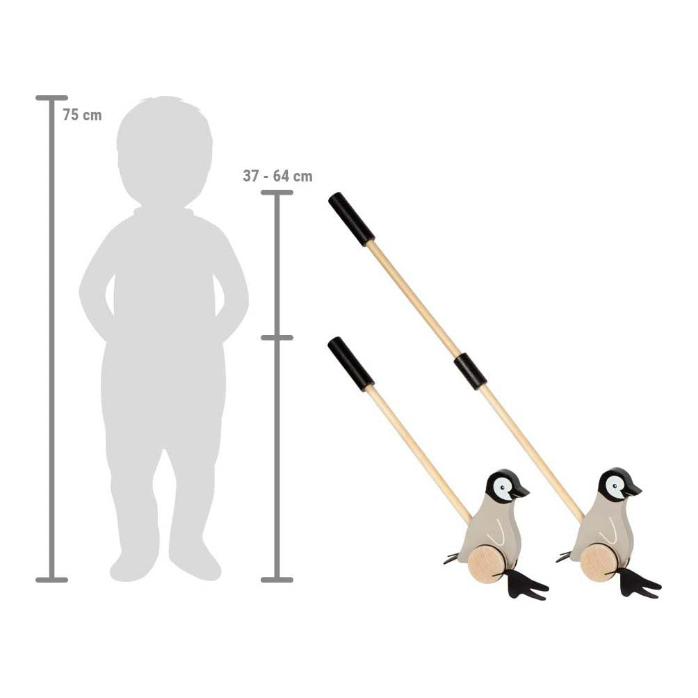 Criança a empurrar o pinguim de madeira, que desliza pelo chão, ilustrando o movimento das patas articuladas e o incentivo à motricidade grossa.