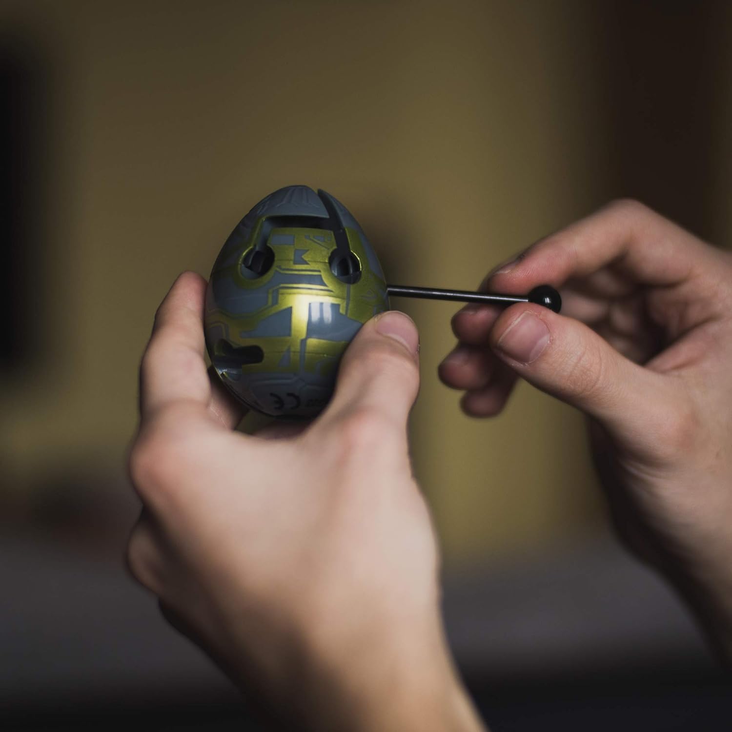 Detalhe de um Smart Egg sendo manipulado, mostrando a varinha e o labirinto interno.