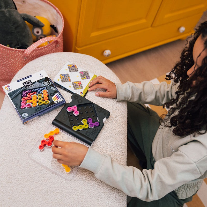 Criança a jogar ao puzzle IQ Gears, colocando as peças de engrenagem coloridas no tabuleiro de jogo.