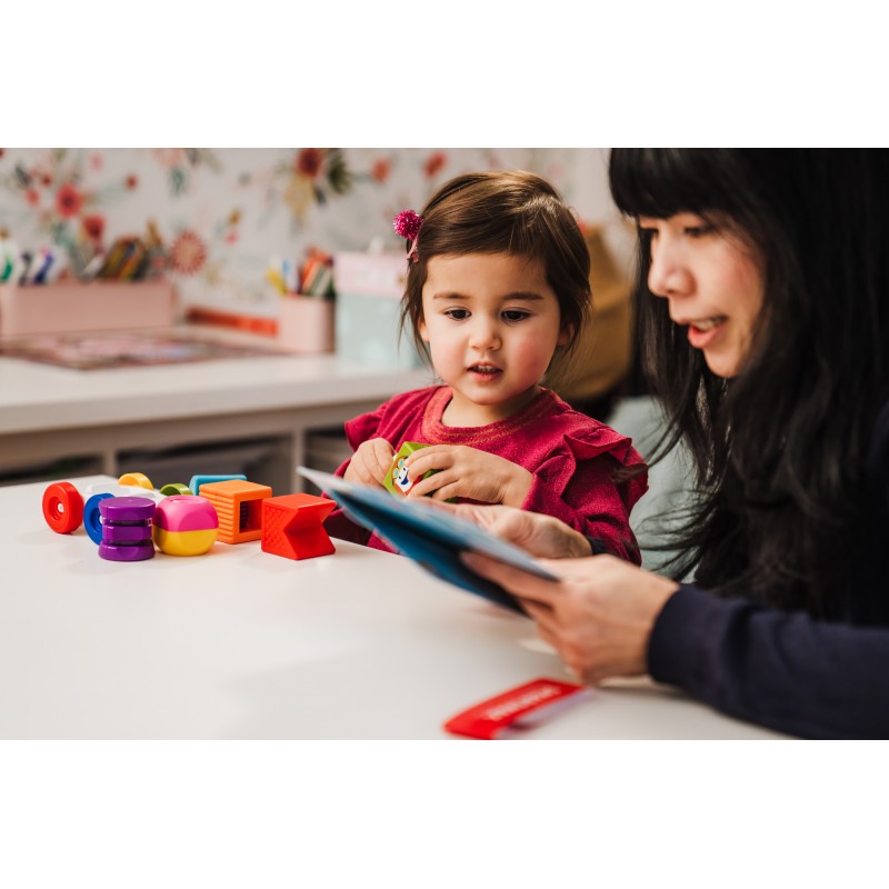 Criança pequena brincando com o SmartMax My First Build & Drive, acompanhada por um adulto.  Mostra o uso interativo do brinquedo.