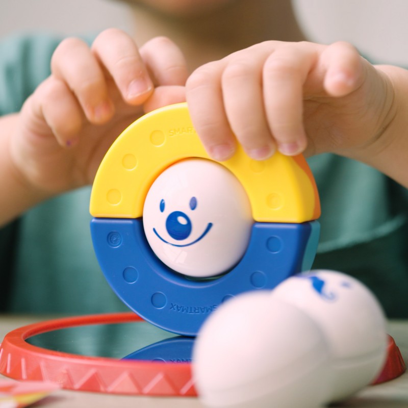 Detalhe das mãos de uma criança a montar uma peça do SmartMax My First Acrobats, mostrando a facilidade de uso e o design ergonômico.