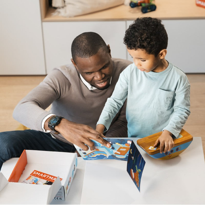 Pai e filho a explorar o folheto de histórias incluído no SmartMax My First Pirates.