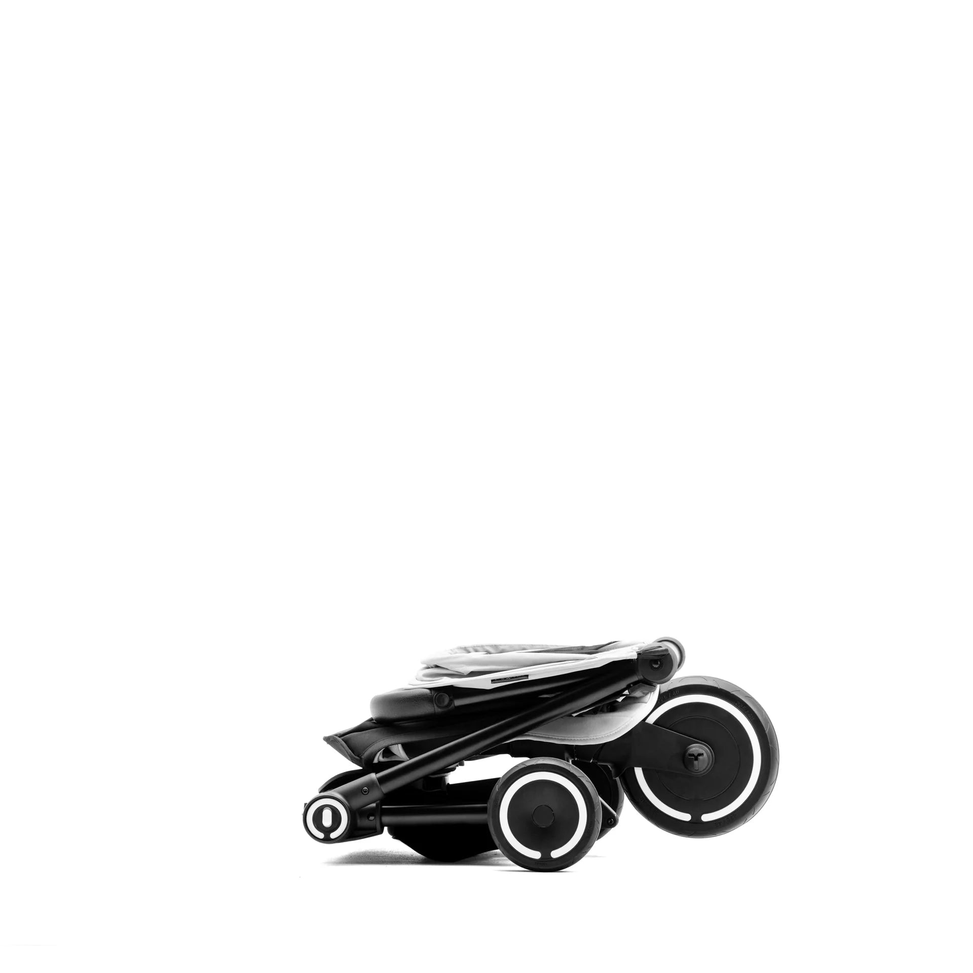 SMARTRIKE TRAVELER carrinho compacto dobrado em cinzento claro, perfil lateral, evidenciando o mecanismo de fecho.