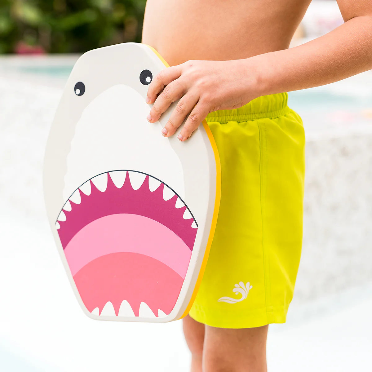 Criança em pé junto à piscina, segurando a prancha de natação Splash About Kickboard Shark Grey ao lado do corpo, mostrando o tamanho.
