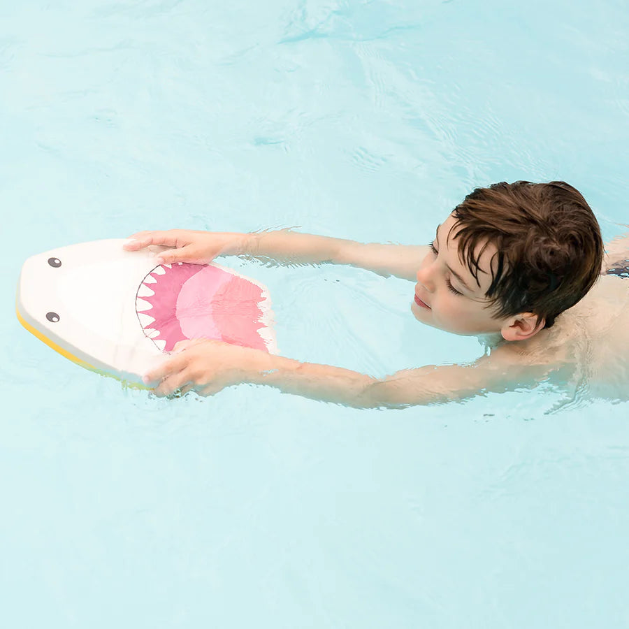 Criança a nadar de lado numa piscina, usando a prancha de natação Splash About Kickboard Shark Grey para apoio.