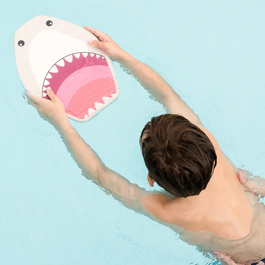 Criança a nadar numa piscina, segurando a prancha de natação Splash About Kickboard Shark Grey com o design de tubarão virado para a frente.