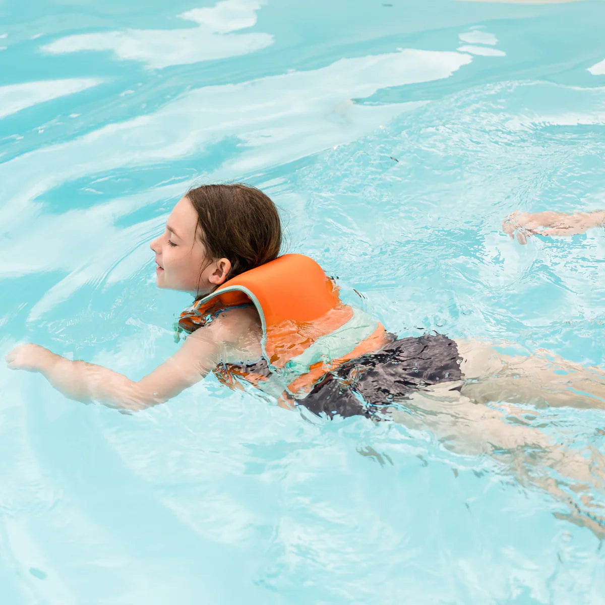 Menina a nadar na piscina a usar o colete natação Splash About Go Splash Adjustable Swim Vest Laranja e Verde.