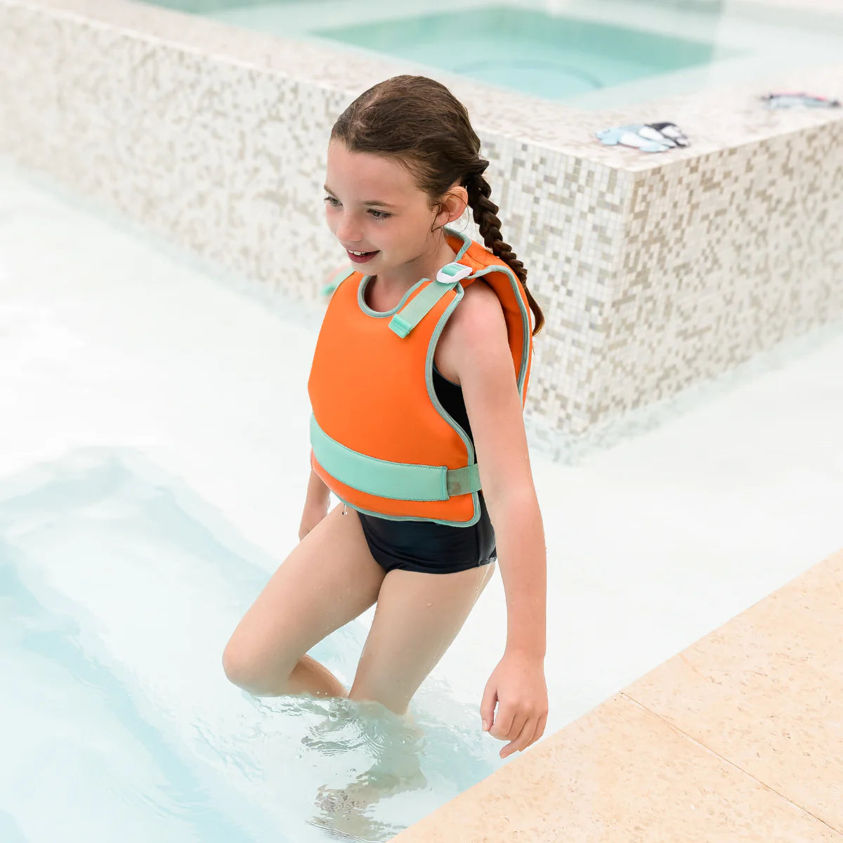Menina a sair da piscina a usar o colete natação Splash About Go Splash Adjustable Swim Vest Laranja e Verde.