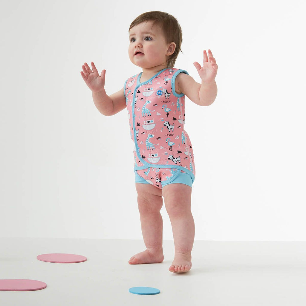 Bebé de 6-18 meses a usar o fato de banho térmico Baby Wrap™ Nina's Ark, rosa com padrão de animais, em estúdio.