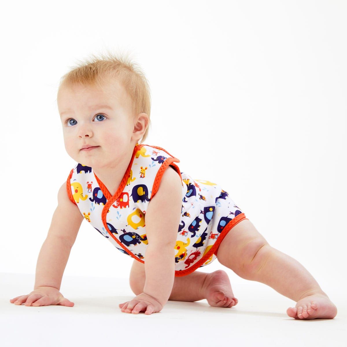 Bebé de olhos azuis a gatinhar, usando o fato térmico Baby Wrap™ de elefantes, evidenciando a mobilidade proporcionada pelo design.