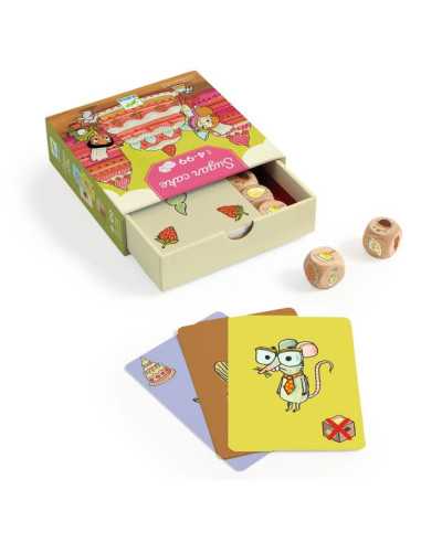 Caixa deslizante do jogo Djeco Sugar Cake aberta, mostrando os componentes internos, com alguns dados e cartas espalhados ao lado.
