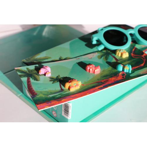 Detalhe dos óculos de sol Sumsun azuis pousados sobre a caixa de arrumação aberta, revelando os acessórios de dinossauro no interior.