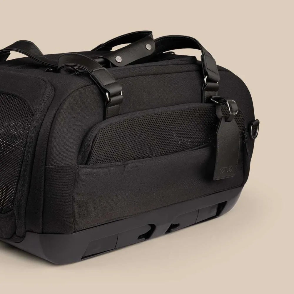 Detalhe do transportador TAVO Dupree II na cor Onyx (preto), com alças em couro vegan e etiqueta de identificação pendurada.