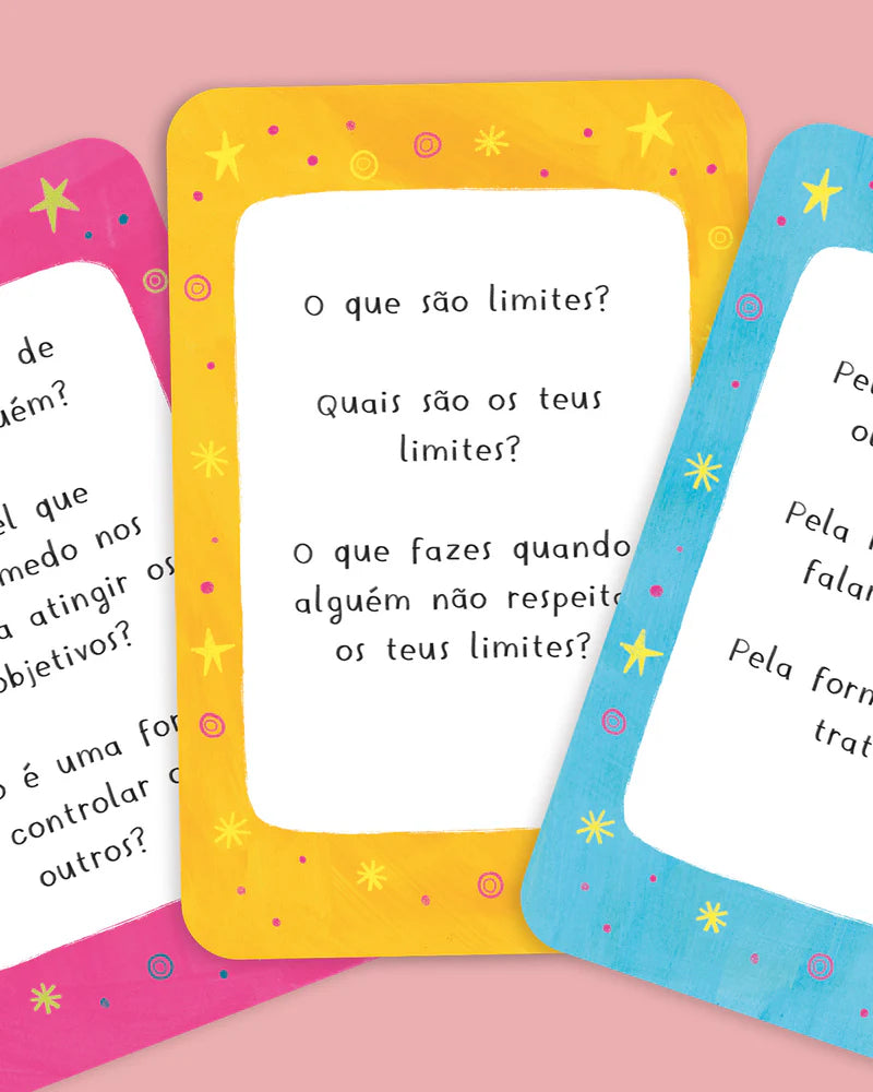 Close-up de três cartas do jogo de reflexão "Tu Podes Mudar o Mundo" com perguntas sobre limites e desenvolvimento emocional.