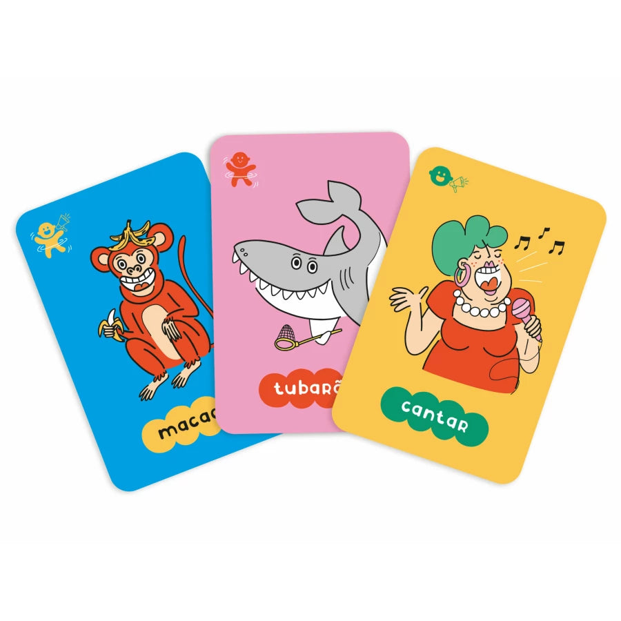 Três cartas do jogo de mímica em primeiro plano: uma com um macaco a comer banana, outra com um tubarão e outra com uma mulher a cantar.