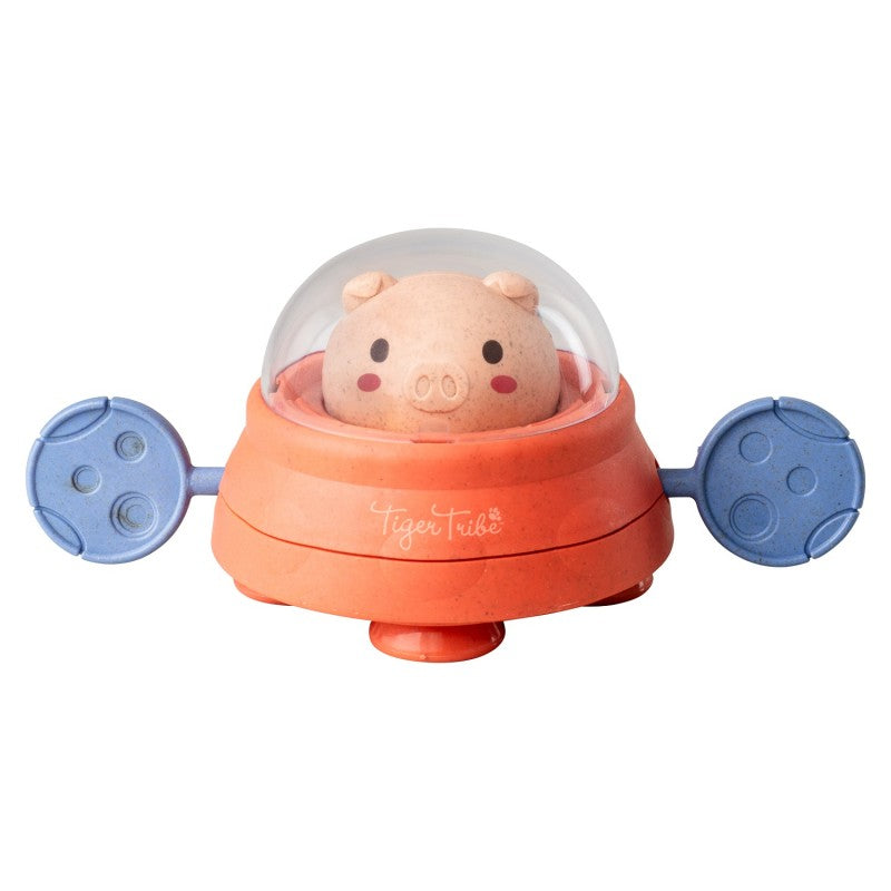 Close-up do brinquedo de banho Space Piggy com porco rosa no cockpit e remos laterais azuis visíveis.