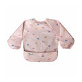 Babete impermeável Tiny Twinkle rosa com mangas, estampado com pequenos unicórnios coloridos, visto de frente.