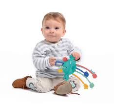 Bebé sorridente, sentado, a segurar e interagir com o Ludi Brinquedo de puxar - estimulação.