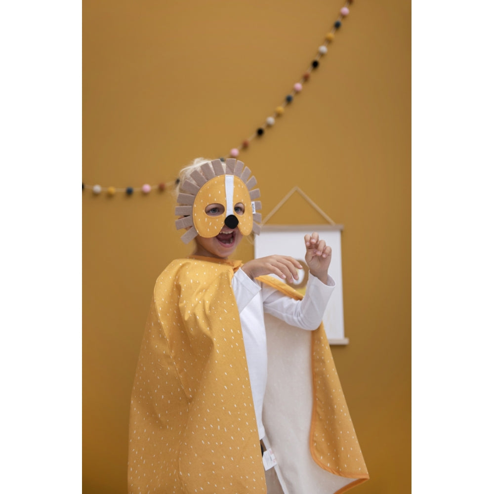 Criança usando a capa e máscara de leão amarela da Trixie, sorrindo e brincando.