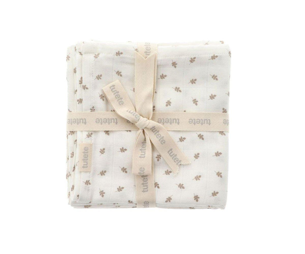 Vista frontal detalhada do conjunto de 2 musselinas brancas com padrão de folhas castanhas, firmemente atadas com fita de marca, destacando a textura suave do tecido.