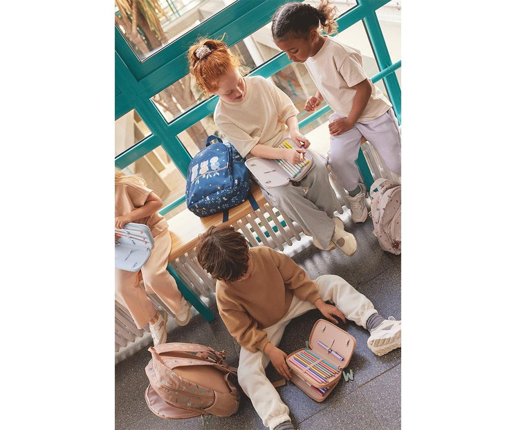 Grupo de crianças na escola a interagirem com mochilas e estojos Tutete, demonstrando o uso social do material escolar.
