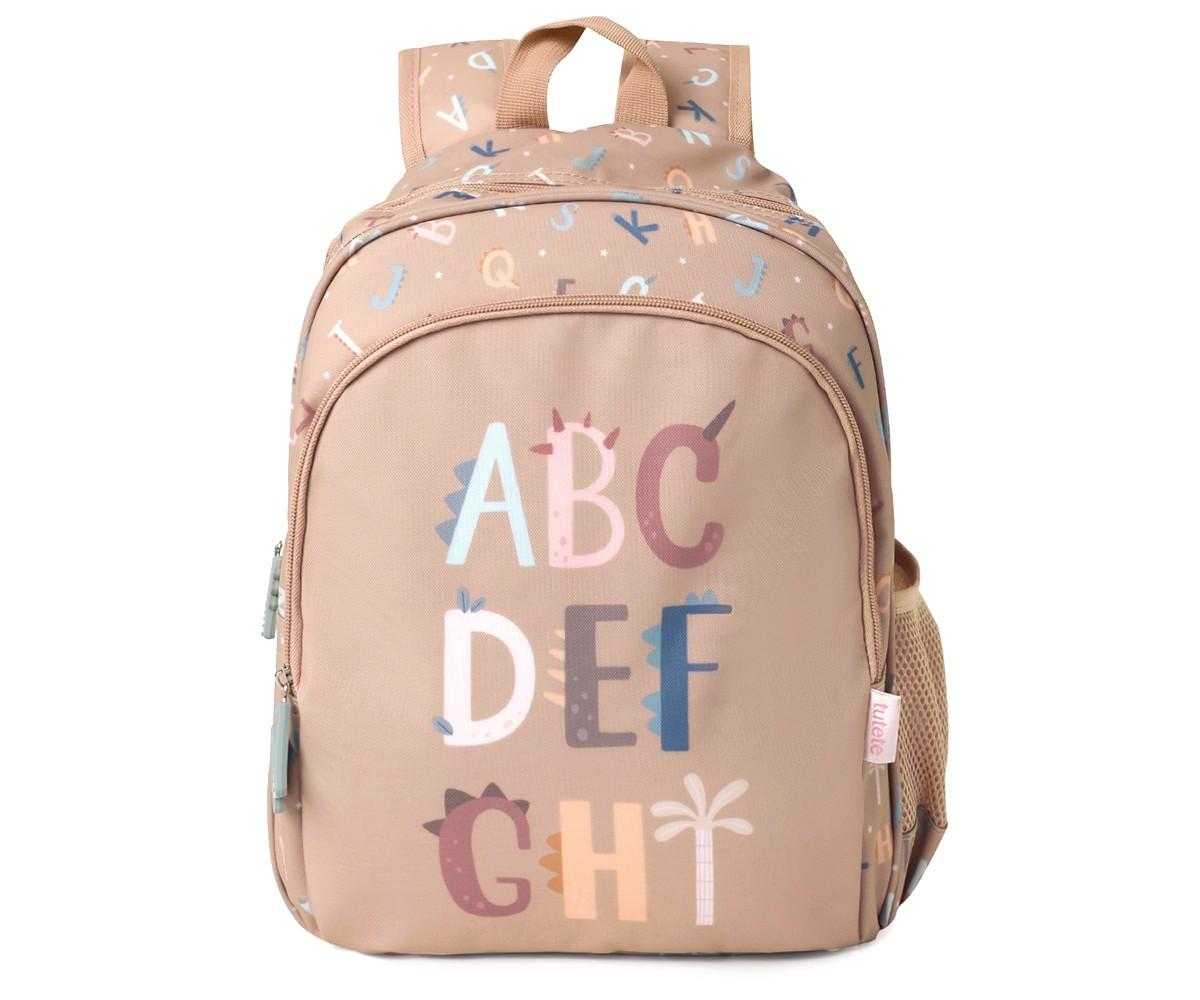 Mochila escolar Tutete bege com padrão de letras e dinossauros, exibindo "ABC DEF GHI" na frente.