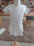 Vestido infantil Hublot branco com estrelas azuis, manga curta, em manequim, mostrando o corte com folho na bainha.