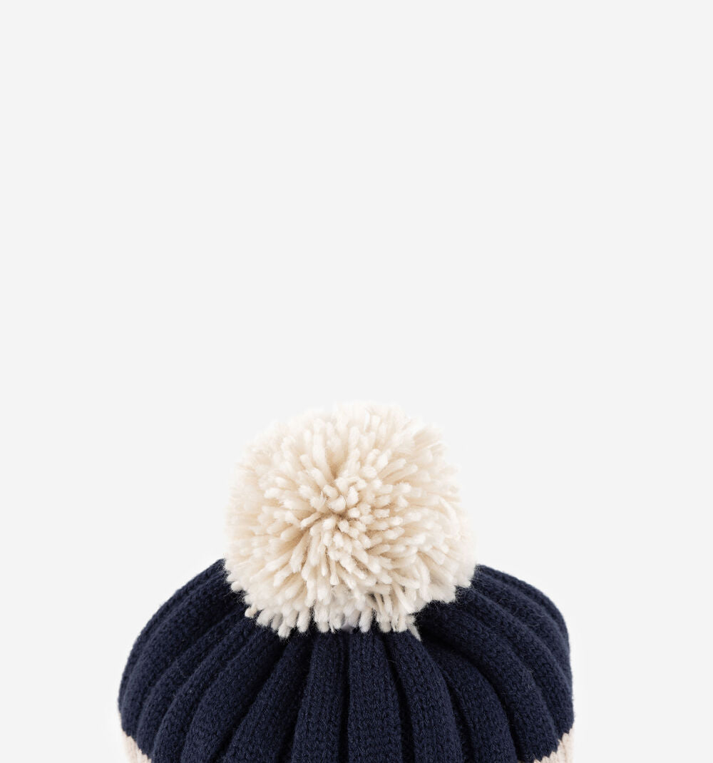 Detalhe do pompom macio e volumoso no topo do gorro Victoria para criança em azul marinho.