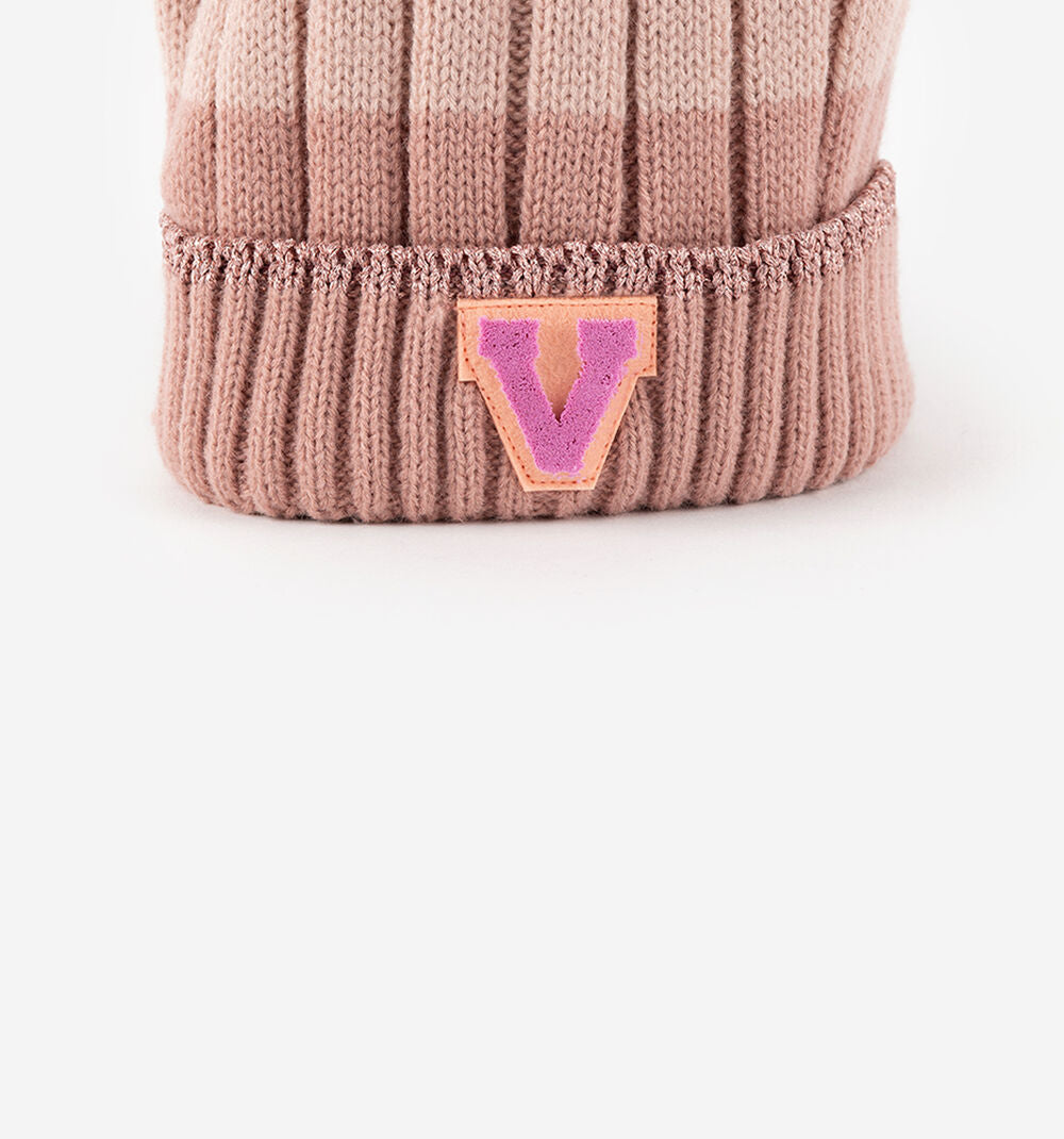 Detalhe do aplique "V" da marca Victória no rebordo em malha do gorro Victoria cor-de-rosa.