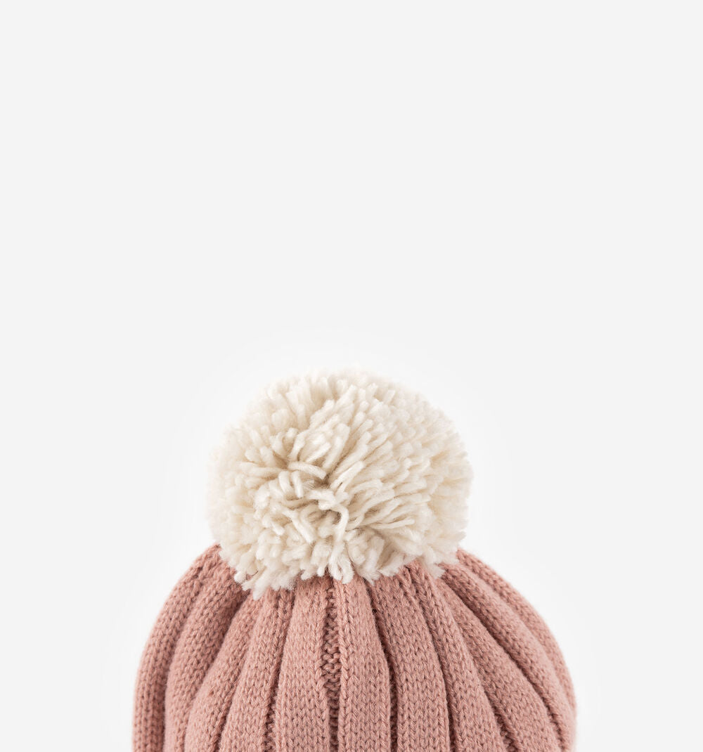 Detalhe do pompom macio e volumoso no topo do gorro Victoria para criança em tons de rosa.