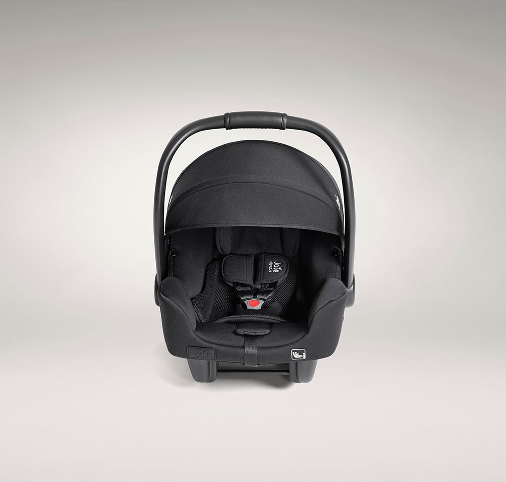 Vista frontal da cadeira auto ovo Joie i-Starter preta, mostrando o arnês de 3 pontos e o apoio de cabeça com o logótipo da folha.