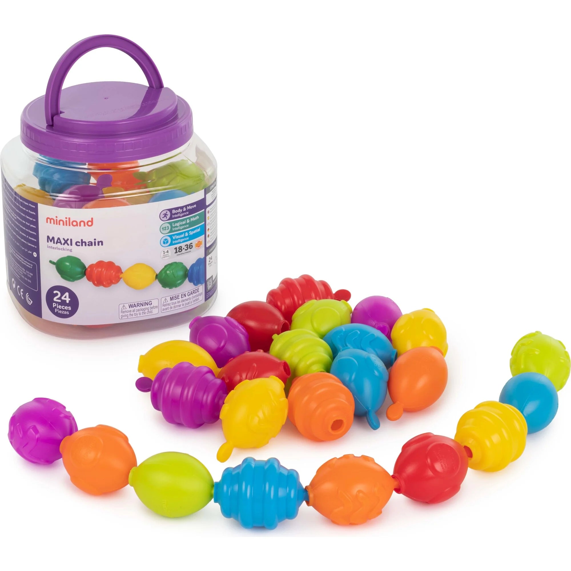 O conjunto completo de Miniland Maxichain Contas 24 peças, com as contas coloridas espalhadas e algumas encaixadas, ao lado do seu recipiente de armazenamento transparente com tampa roxa e alça, visível a etiqueta com a idade recomendada.