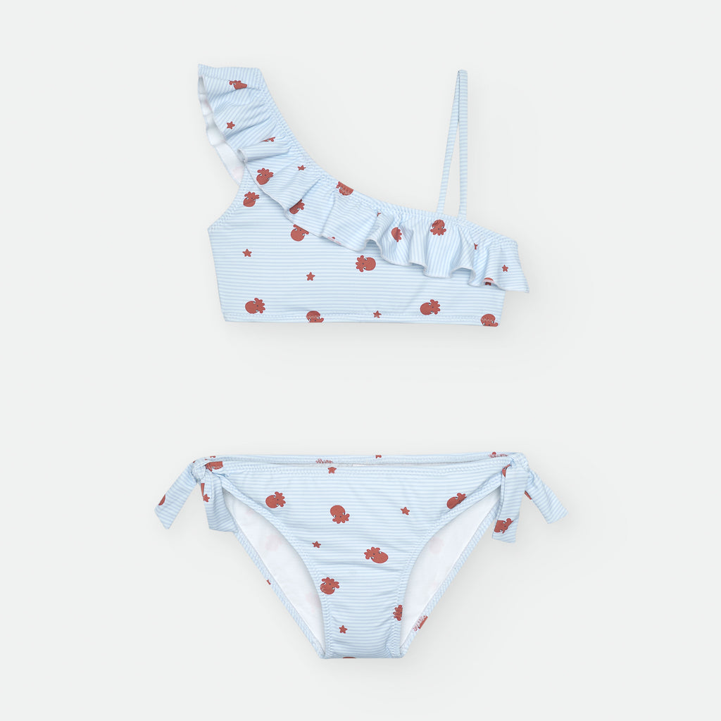 Biquini Waterlemon infantil azul claro, com top assimétrico com folho e cueca com laços. Estampado com polvos e estrelas. Vista frontal.