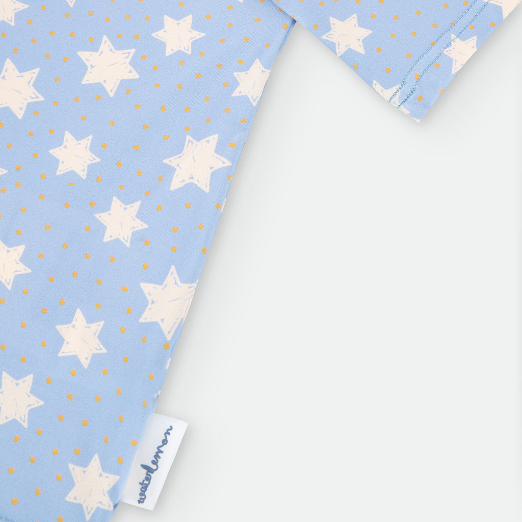 Detalhe em close-up da costura raglan e da etiqueta Waterlemon na bainha da camisola de proteção solar com padrão de estrelas.