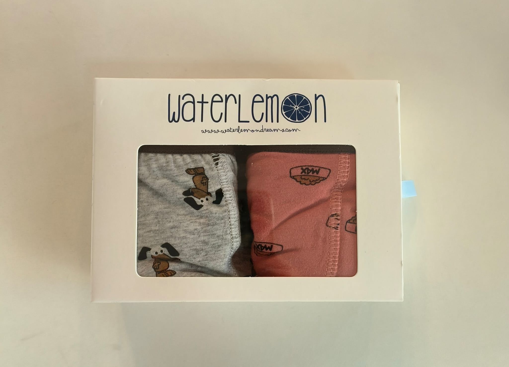 Detalhe de dois boxers Waterlemon na caixa: um cinzento com padrão de cães e um rosa com padrão de dentes de tubarão e cós "XPW".