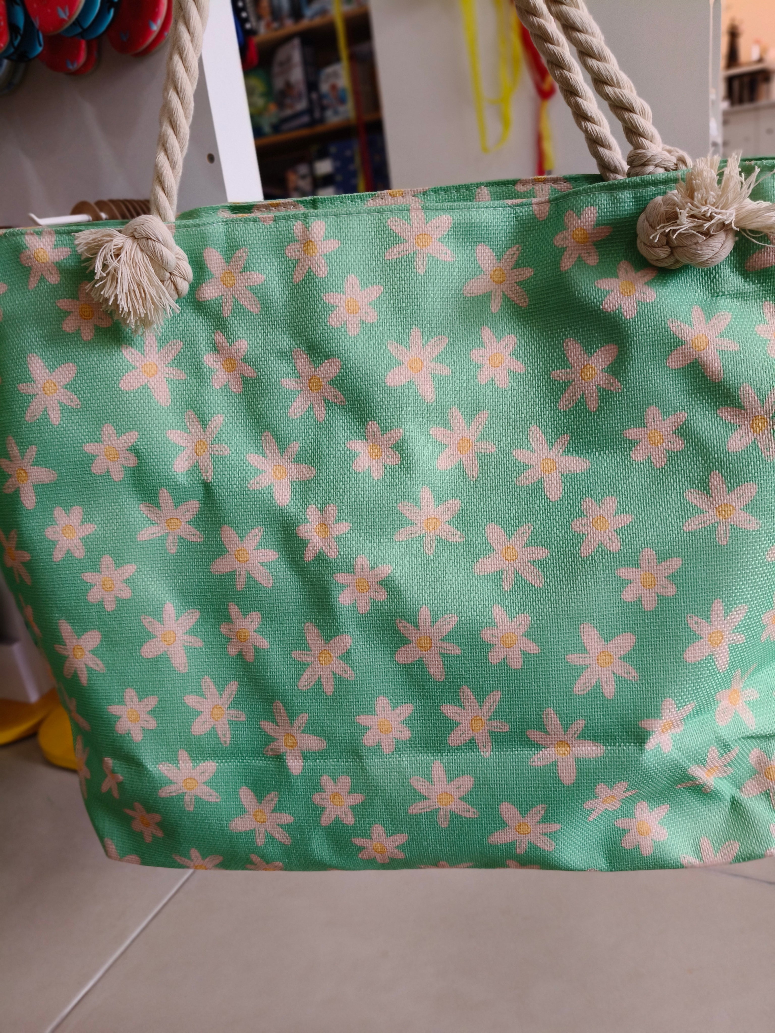 Saco de praia Waterlemon verde-água com padrão de margaridas brancas e centro amarelo, com alças de corda grossa.