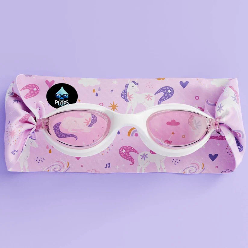 Óculos de natação Waterplops brancos com lentes cor-de-rosa, colocados sobre a sua bolsa/embalagem de tecido com estampa de unicórnios.