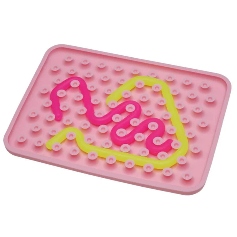 Detalhe do Wiggly Toy em base rosa, com peças sensoriais rosa choque e amarela, ideal para motricidade fina.