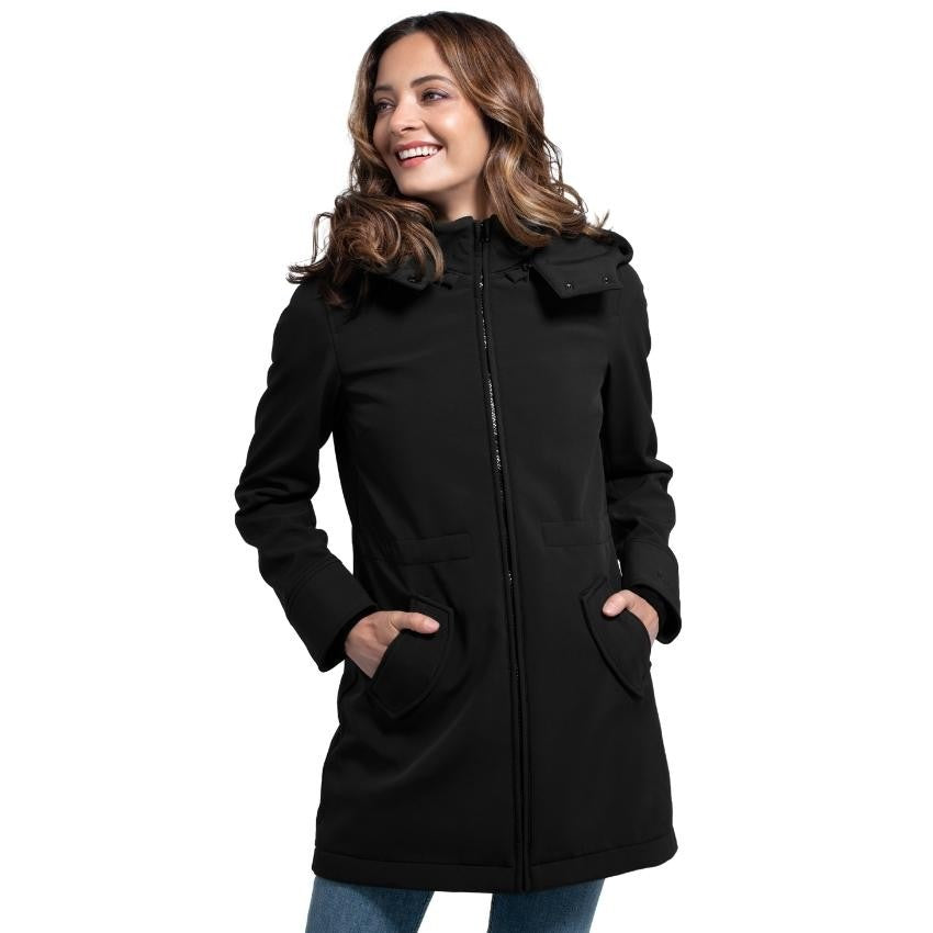 Mulher sorridente com casaco Wombat Shell preto, sem painel de transporte, com as mãos nos bolsos, estilo casaco normal.