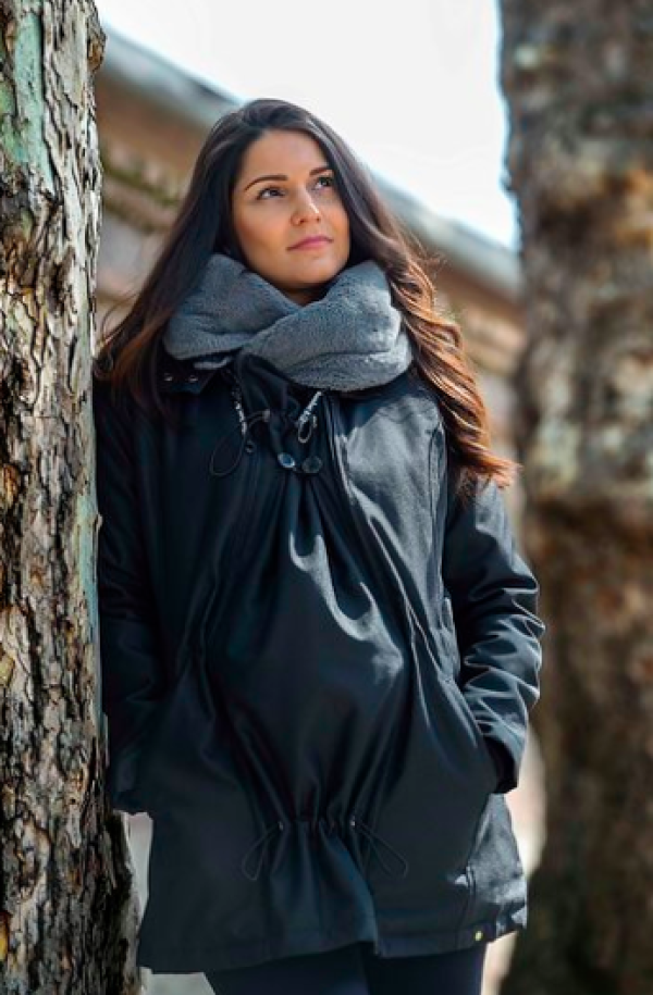 Mulher com casaco Wombat Wallaby 2.0 preto, encostada a uma árvore, exibindo o estilo normal do casaco.