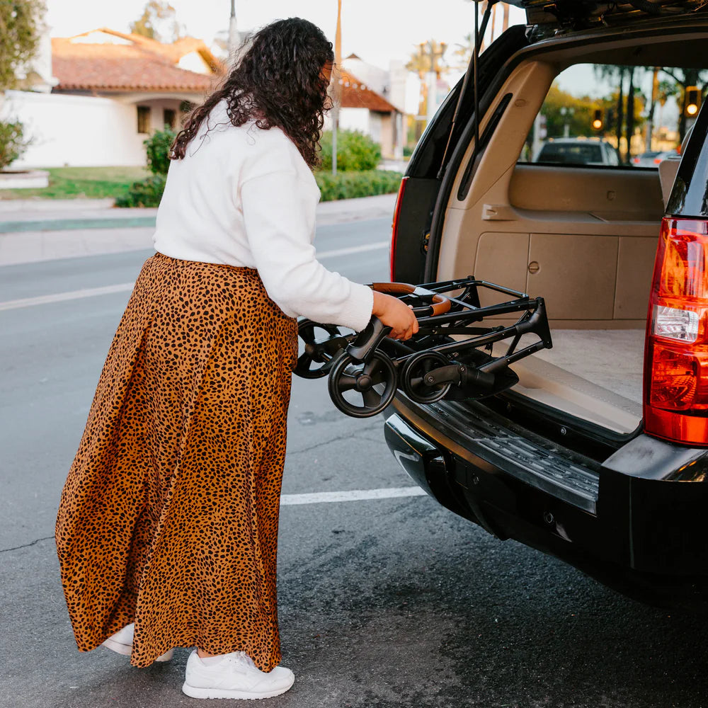 Mulher a dobrar a estrutura do carrinho Wonderfold P2 para guardar na mala do carro.