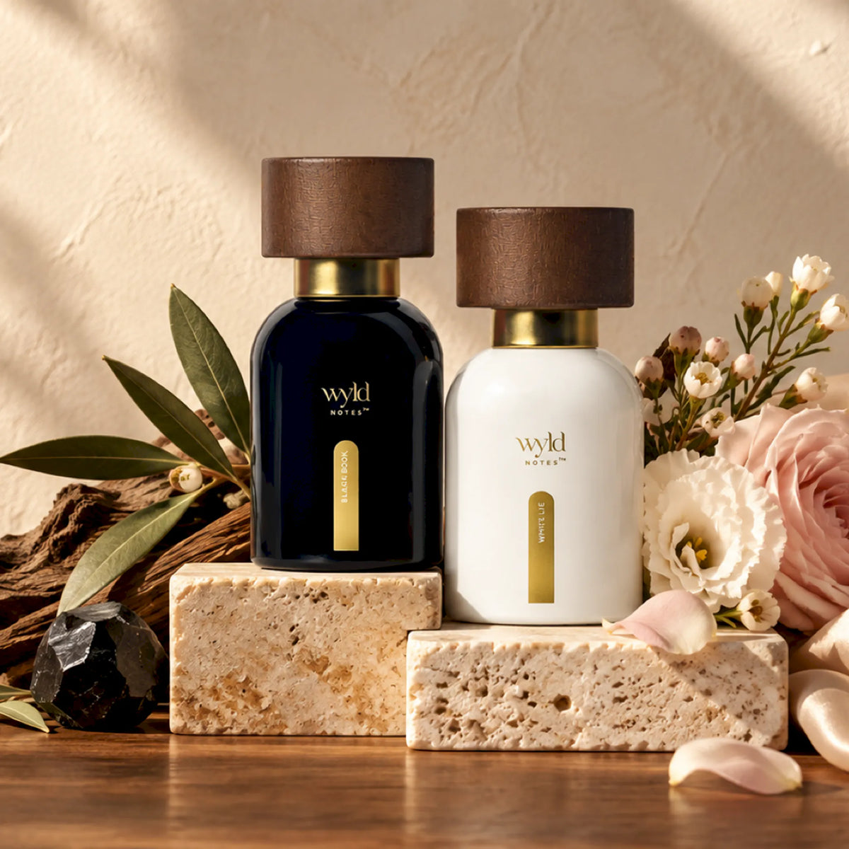 Os dois perfumes do conjunto His and Hers pousados em pedra, com flores e ramos verdes em luz natural