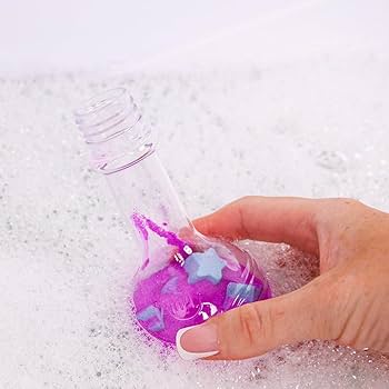 Uma mão segura uma garrafa de poção transparente cheia de líquido roxo e estrelas azuis, submersa em água com espuma de banho.