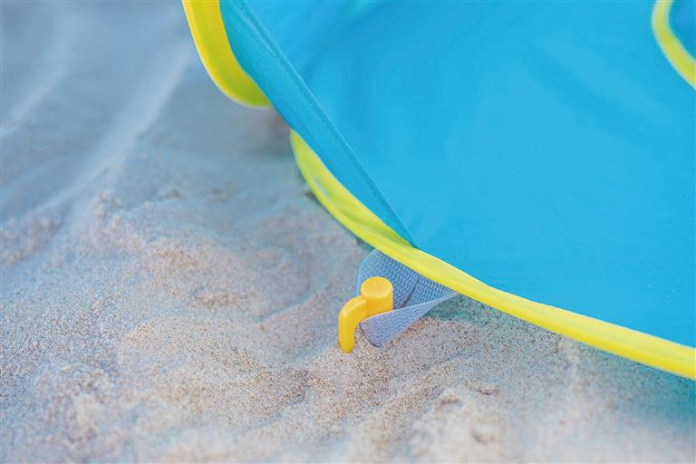 Detalhe de uma estaca da Olmitos Tenda Piscina Pop Up fixada na areia da praia.
