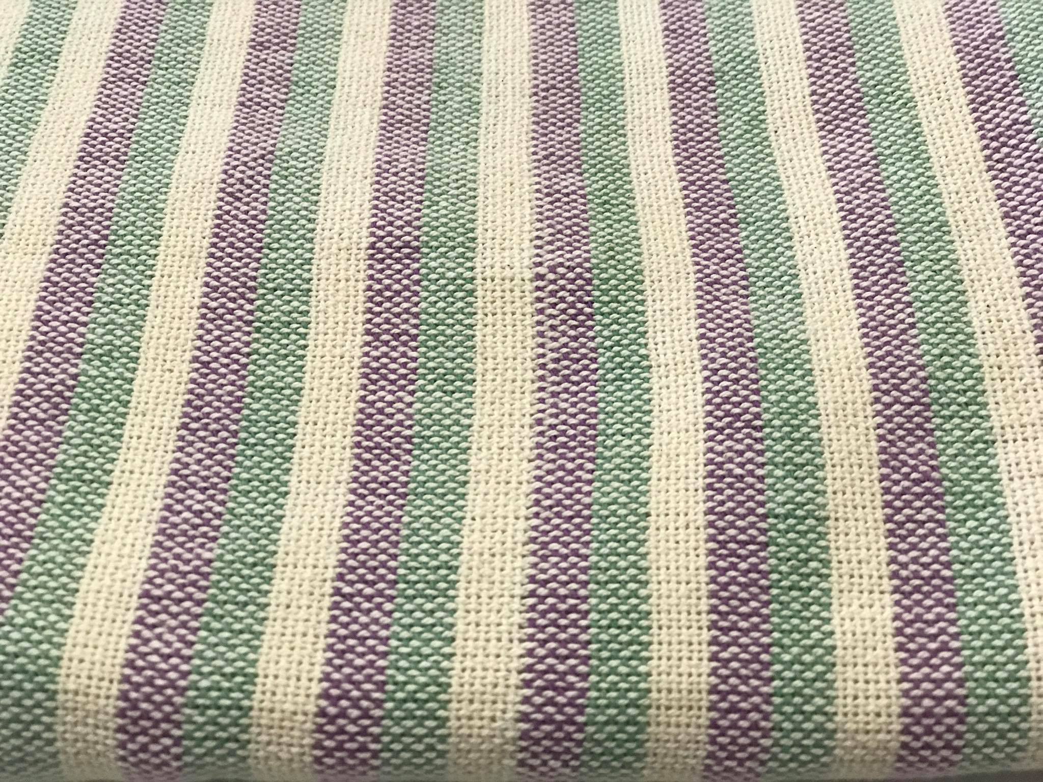 Detalhe de um pano tecido com riscas em tons de rosa e verde, mostrando a textura e a qualidade do tecido.